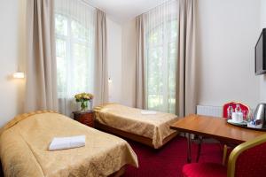 马佐夫舍地区新庄园莫德林宫酒店的酒店客房设有两张床和一张桌子。