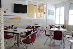 泰拜尔盖马辛旅舍的一间带桌椅的餐厅以及墙上的电视