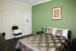 布里斯班汉普顿酒店式公寓的一间卧室配有一张床和一把椅子