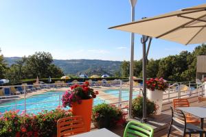 纳雅克VVF Aveyron Najac的享有酒店游泳池的景色,设有桌椅