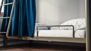 普里什蒂纳ODA Hostel的客房内的双层床配有蓝色窗帘