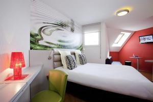 圣布里厄圣布里厄火车站中心宜必思尚品酒店的卧室配有一张白色大床和一张绿色椅子