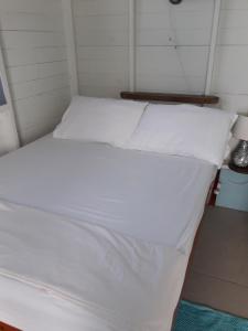 圣乔治Cosy Hut的配有白色床单和枕头的宿舍间内的一张床位