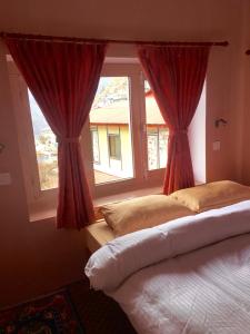 NamcheHotel Khangri的一间卧室设有两张床,窗户配有红色窗帘
