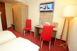 布拉河畔的海登海姆赫希酒店的酒店客房配有书桌和2把红色椅子