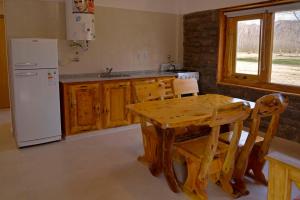 格兰德山谷Cabañas Posada del Angel的厨房配有木桌和白色冰箱。