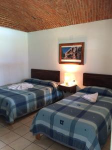 特基斯基亚潘Hotel Los Mezquites的酒店客房设有两张床,墙上挂着一张照片。