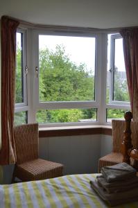 邓弗姆林Holiday Apartment Dunfermline的一间卧室配有两把椅子、一张床和两个窗户。