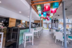 马斯帕洛马斯Hotel LIVVO Los Calderones - Adults recommended的一间设有白色椅子的餐厅和一间拥有色彩缤纷灯光的酒吧