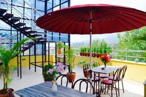 加德满都富豪机场酒店的庭院配有带红色遮阳伞的桌子