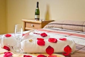 阿尔赫西拉斯马日亚路易撒酒店的一张带玫瑰的睡床和一瓶葡萄酒