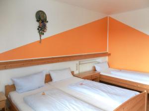 达辛格兰德盖斯豪弗艾斯姆酒店的橙色墙壁的客房内的两张床