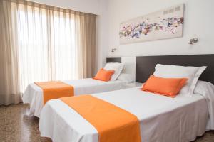 瓦伦西亚瓦伦西亚Pio XII公寓式酒店的橙色和白色的酒店客房内的两张床
