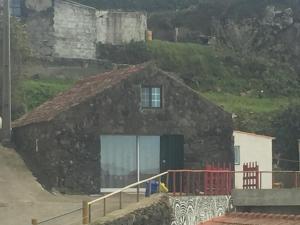 Lajes das FloresHouse with Forest View的一座带窗户和围栏的石头房子