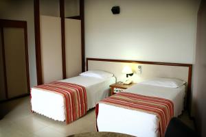 伊通比亚拉Hotel Beira Rio的酒店客房设有两张床和一张带台灯的桌子。