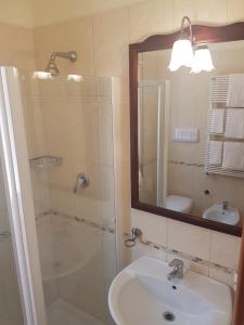 圣乔瓦尼·罗通多Hotel Rosamarina的浴室配有盥洗盆和带镜子的淋浴