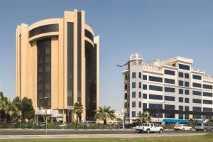 阿可贺巴Ramada by Wyndham Al Khobar的一座大型建筑,前面有汽车停放