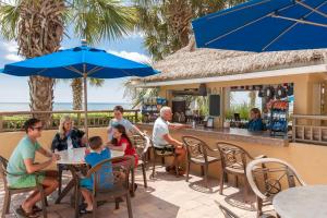 默特尔比奇Holiday Pavilion Resort on the Boardwalk的一群人坐在一间有蓝色遮阳伞的餐厅里
