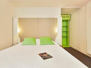 艾克斯莱班钟楼埃克斯勒班酒店的一张带绿色枕头的床和一本书