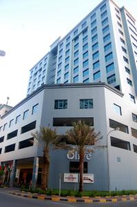 麦纳麦The Olive Hotel, Juffair的一座白色的大建筑,前面有棕榈树