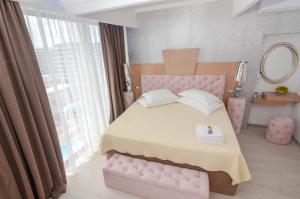 北马马亚-讷沃达里菲尼基豪华酒店的卧室配有粉红色的床和镜子