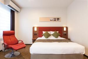 东京MYSTAYS 羽田酒店的一间卧室配有一张床和一张红色椅子