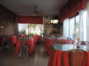 维拉卡洛斯帕兹Hotel Carlos Paz的一间设有红色桌椅和窗户的用餐室