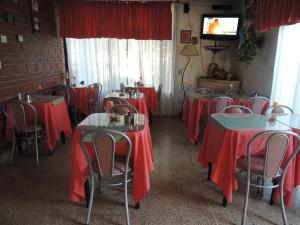 维拉卡洛斯帕兹Hotel Carlos Paz的餐厅设有红色的桌椅和电视