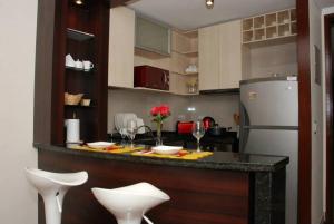 圣地亚哥Puerta Arauco Apartamentos的厨房配有带白色椅子和冰箱的酒吧