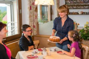 米尔施塔特盖茨弗莱德住宿加早餐酒店的把蛋糕给餐桌上的小女孩的女人