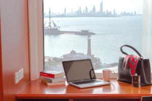 科威特ibis Kuwait Salmiya的坐在窗边的桌子上的笔记本电脑