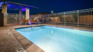 加迪纳市Best Western Plus Gardena-Los Angeles Inn & Suites的游泳池在晚上配有两把椅子和一张桌子