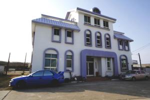 马公驫風民宿 Equuleus Homestay的停在白色房子前面的蓝色汽车