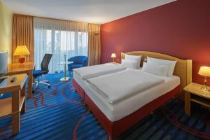 柏林柏林滕珀尔霍夫美居酒店的配有一张床和一张书桌的酒店客房