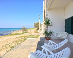玛丽娜迪曼卡维萨Appartamento Patrizia的两把白色椅子坐在海边的房子边