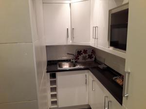 利物浦利物浦酒店的厨房配有白色橱柜、水槽和微波炉