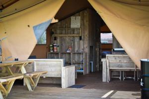 OostvleterenGlamping Aan de Vleterbeke的客房内的帐篷配有长凳和桌子