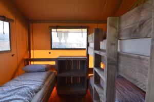 OostvleterenGlamping Aan de Vleterbeke的小房间设有两张双层床和窗户