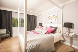 克里克豪厄尔曼诺酒店的卧室配有带粉红色枕头的大型白色床