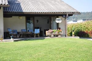 韦尔特湖畔克伦彭多夫Seebungalows Wedenig direkt am See的房屋设有带椅子和桌子的庭院