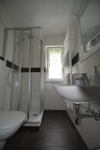 普罗勒布谢尔旅馆的白色的浴室设有水槽和淋浴。