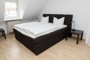 卡塞尔泽林内霍夫旅馆的一张黑色的床,配有白色床单和枕头