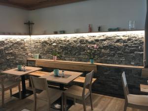 施特罗布尔丽丽湖畔酒店的一间设有两张桌子和椅子的餐厅以及石墙