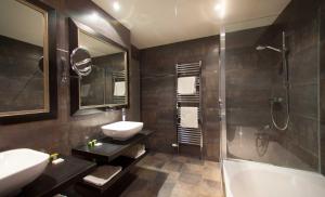 朗格勒Logis Hôtel Le Cheval Blanc的浴室配有水槽、淋浴和浴缸。