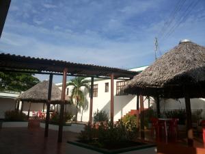 IníridaHotel Orinoco Real的一座带两把稻草伞和桌椅的建筑