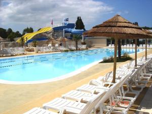 莱马特Beau mobilhome La Palmyre 4 étoiles的一个带白色躺椅的游泳池,一个度假村