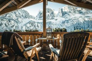 科尔福索Kolfuschgerhof Mountain Resort的门廊上的两把椅子,享有山景