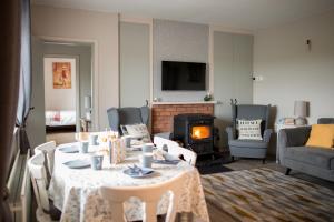 利斯坎诺Rose Meadow Cottage的客厅配有桌子和壁炉