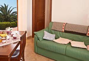 奥尔梅多Agriturismo Sa Suerera的客厅配有一张绿色沙发,设有一张桌子
