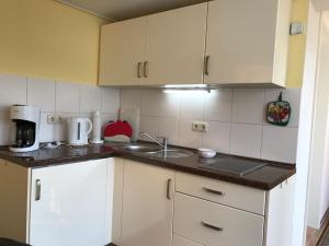 普雷罗Zum Nordstrand的小厨房配有白色橱柜和水槽